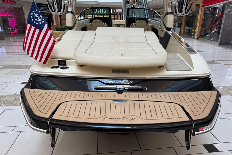 Slide: The Image of 2026 Chris-Craft Sportster 25 boat displayed indoors with American flag. - 24