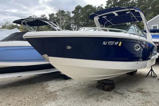 The Image of 2021 Chaparral 267 SSX boat with blue hull, parked on gravel. - 0