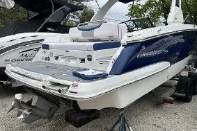 Slide: The Image of 2021 Chaparral 267 SSX boat, white and blue, docked outdoors. - 2