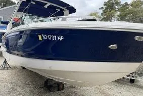 Slide: The Image of 2021 Chaparral 267 SSX boat with blue hull, docked on gravel. - 3