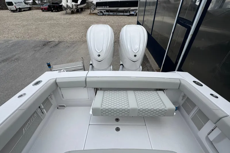 Slide: The Image of 2026 Jupiter 30 boat with dual engines and cushioned seating in a marina setting. - 17