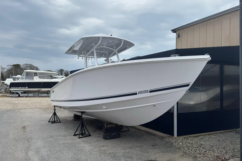 Slide: The Image of 2026 Jupiter 30 boat on stands, displayed outdoors under cloudy skies. - 2
