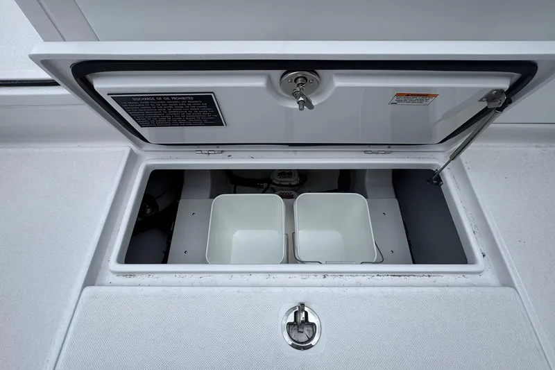 Slide: The Image of Open storage compartment on a 2026 Jupiter 30 boat with two white bins. - 25