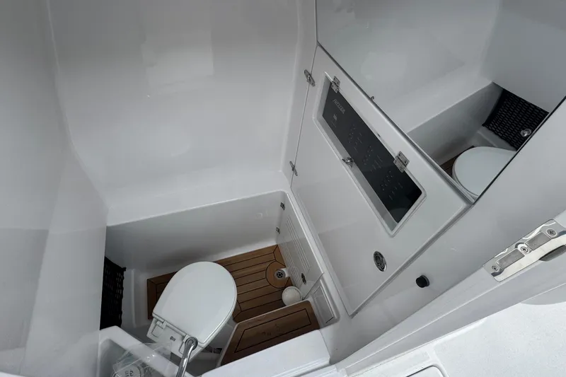 Slide: The Image of 2026 Jupiter 30 boat interior with compact bathroom, featuring a toilet and wooden flooring. - 42
