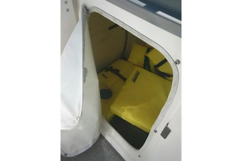 Slide: The Image of Storage compartment with yellow life jackets on a 2019 Robalo R207 Dual Console boat. - 25