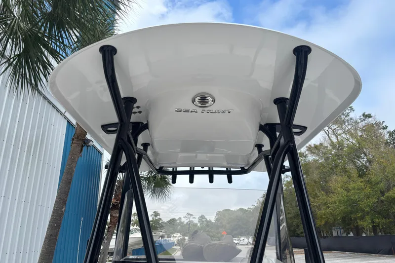 Slide: The Image of 2021 Sea Hunt Ultra 219 T-top view with logo, surrounded by trees and blue sky. - 14
