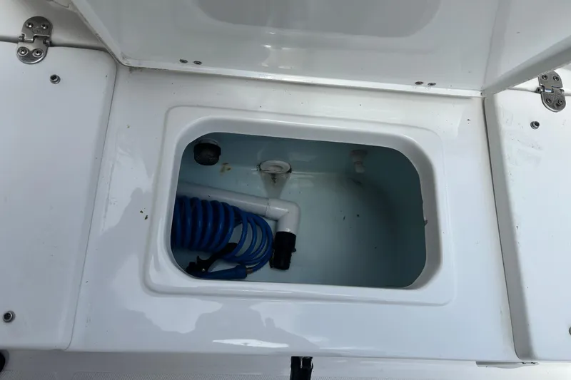 Slide: The Image of Open storage compartment on 2021 Sea Hunt Ultra 219 boat with coiled hose inside. - 20