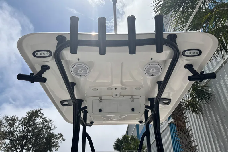 Slide: The Image of 2021 Sea Hunt Ultra 219 boat T-top with rod holders and speakers under a sunny sky. - 8
