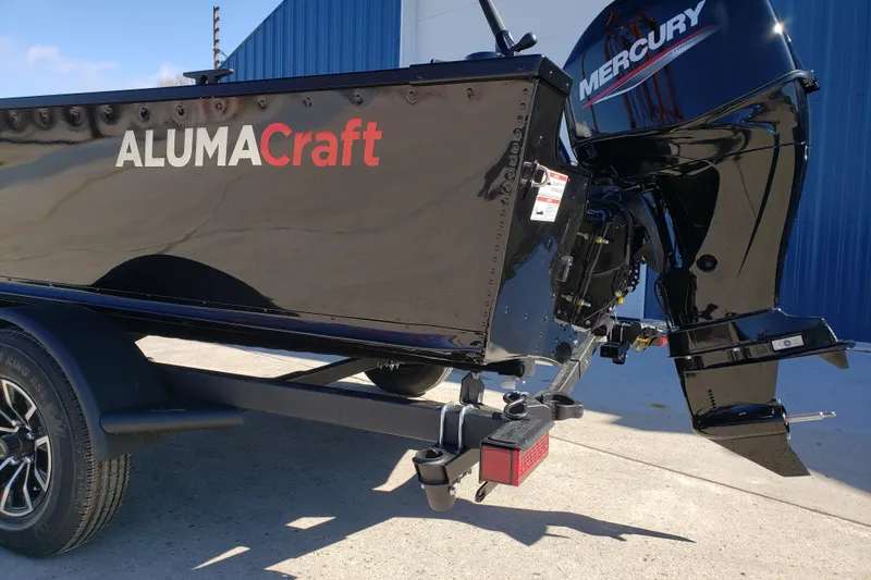 Slide: The Image of 2026 Alumacraft Classic 165 Tiller boat with Mercury engine, parked outdoors. - 13
