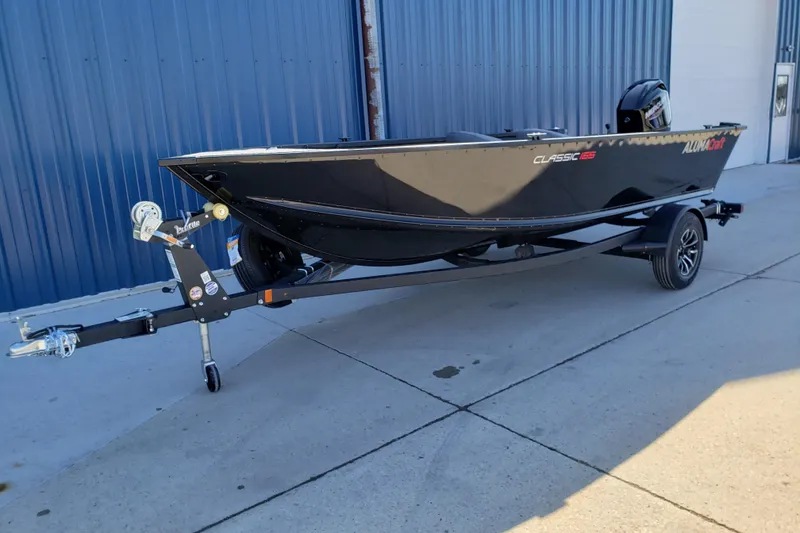 Slide: The Image of 2026 Alumacraft Classic 165 Tiller boat on trailer, parked outdoors. - 6