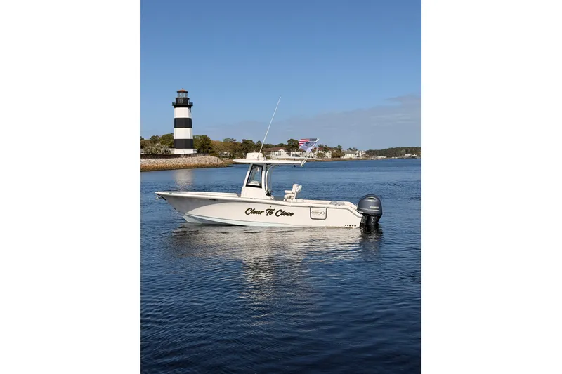 The Image of 2021 Sea Hunt Gamefish 25 boat on water near a lighthouse, clear sky background. - 0