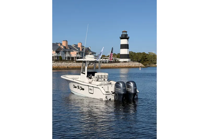 Slide: The Image of 2021 Sea Hunt Gamefish 25 boat near lighthouse and waterfront homes. - 2