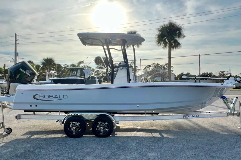 The Image of 2026 Robalo 246 Cayman boat on trailer, parked outdoors under a sunny sky. - 1
