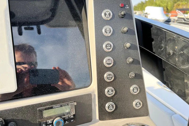 Slide: The Image of Control panel of 2026 Robalo 246 Cayman boat with various switches and a Clarion audio system. - 19