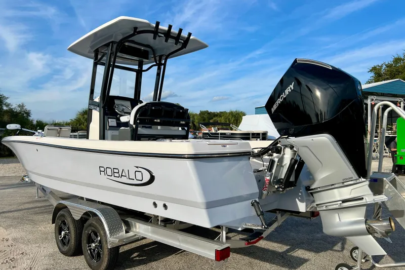 Slide: The Image of 2026 Robalo 246 Cayman boat with Mercury engine on trailer, under clear blue sky. - 6