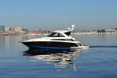 Slide: The Image of 2013 Regal 35 Sport Coupe yacht cruising on calm waters near a city skyline. - 12