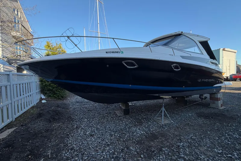 Slide: The Image of 2013 Regal 35 Sport Coupe boat on stands, displayed outdoors on gravel. - 15