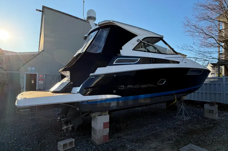 Slide: The Image of 2013 Regal 35 Sport Coupe boat on blocks, side view in a marina setting. - 17