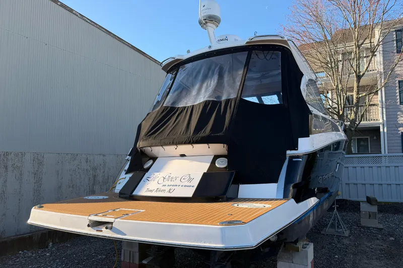 Slide: The Image of 2013 Regal 35 Sport Coupe boat docked, rear view with covered cockpit and wooden deck. - 18