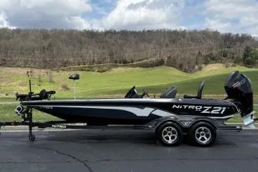 Slide: The Image of 2023 Nitro Z21 XL boat on trailer, parked outdoors with scenic background. - 8