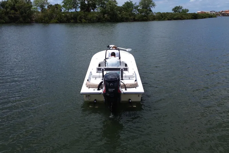 Slide: The Image of 2017 Beavertail Skiffs Lightning boat on calm water, surrounded by lush greenery. - 3