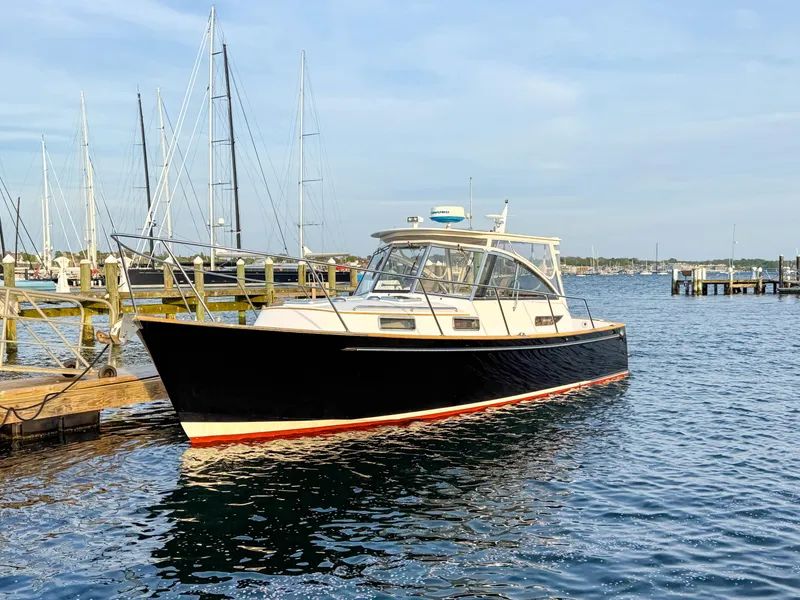 Slide: The Image of 2002 Legacy 34 Express boat docked in a marina, calm water, clear sky. - 1