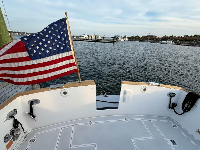 Slide: The Image of 2002 Legacy 34 Express boat deck with American flag, overlooking marina waters. - 11
