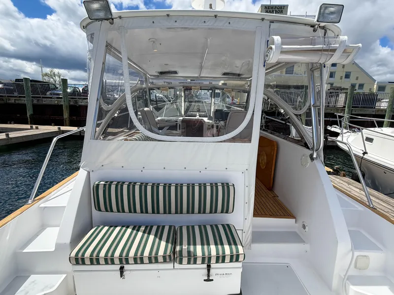 Slide: The Image of 2002 Legacy 34 Express boat with striped seating, docked at a marina. - 12