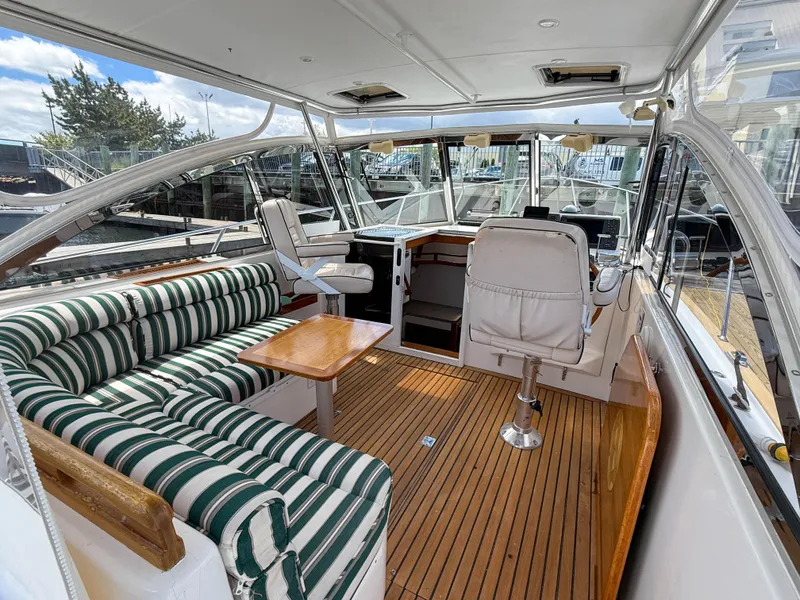 Slide: The Image of 2002 Legacy 34 Express yacht interior with striped seating and wooden flooring. - 13