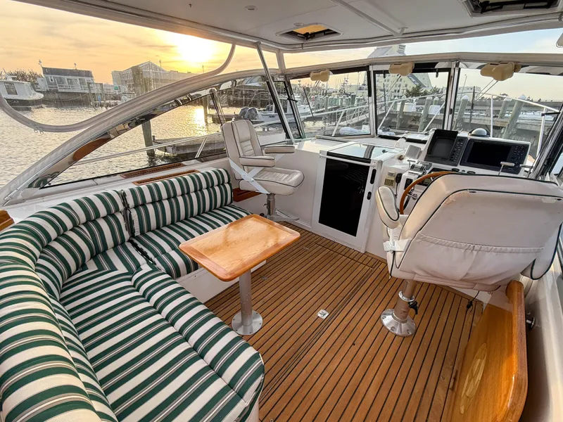 Slide: The Image of Interior of 2002 Legacy 34 Express yacht with striped seating and wooden flooring at sunset. - 14