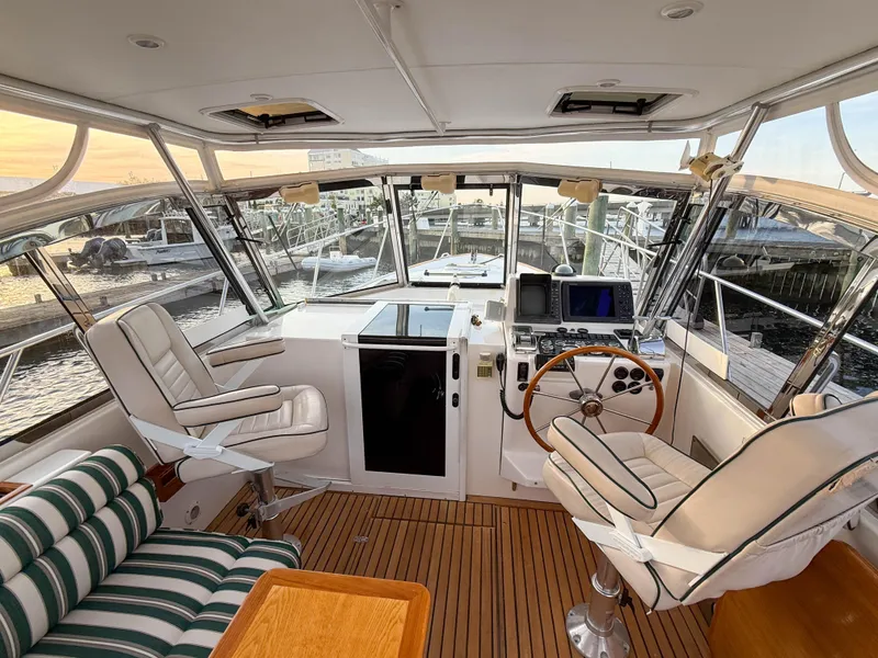 Slide: The Image of 2002 Legacy 34 Express yacht cockpit with helm, seating, and marina view. - 15