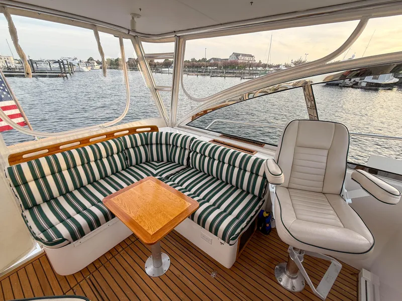 Slide: The Image of 2002 Legacy 34 Express yacht interior with striped seating and wooden table, overlooking marina. - 16