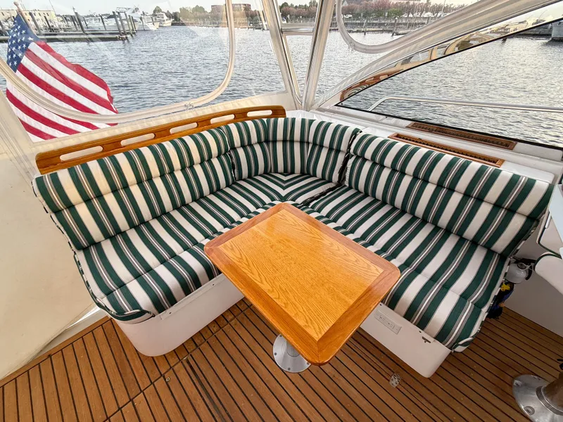 Slide: The Image of Cozy seating area on 2002 Legacy 34 Express boat with striped cushions and wooden table. - 17