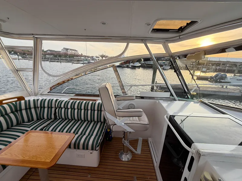 Slide: The Image of Interior of 2002 Legacy 34 Express yacht with striped seating and wooden table, overlooking marina. - 18