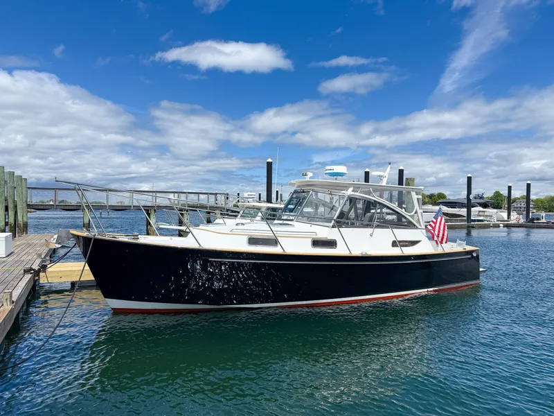 Slide: The Image of 2002 Legacy 34 Express boat docked in a marina under a blue sky. - 2
