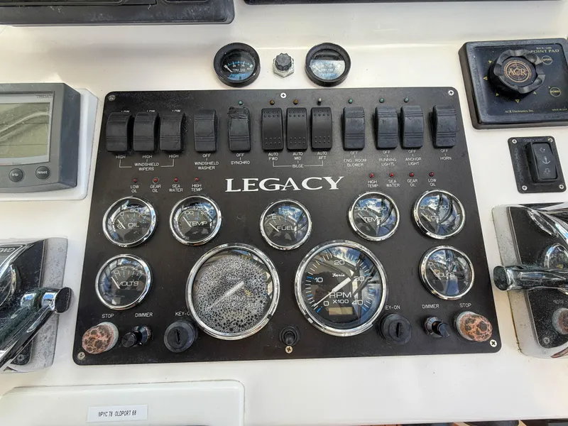 Slide: The Image of Control panel of a 2002 Legacy 34 Express boat with gauges and switches. - 21