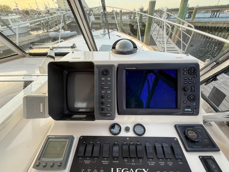 Slide: The Image of 2002 Legacy 34 Express boat dashboard with navigation equipment and controls at a marina. - 22