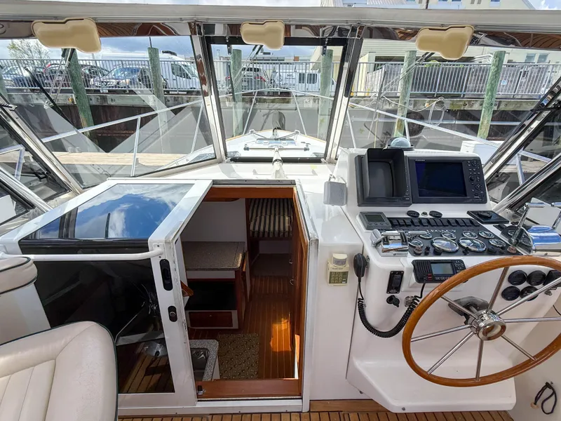 Slide: The Image of 2002 Legacy 34 Express boat cockpit with steering wheel and navigation equipment. - 23