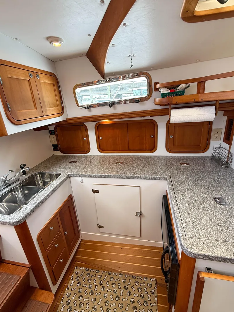 Slide: The Image of 2002 Legacy 34 Express boat kitchen with wood cabinets, dual sink, and countertop. - 27