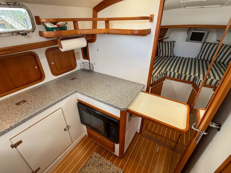 Slide: The Image of 2002 Legacy 34 Express yacht interior with kitchenette and cozy sleeping area. - 31