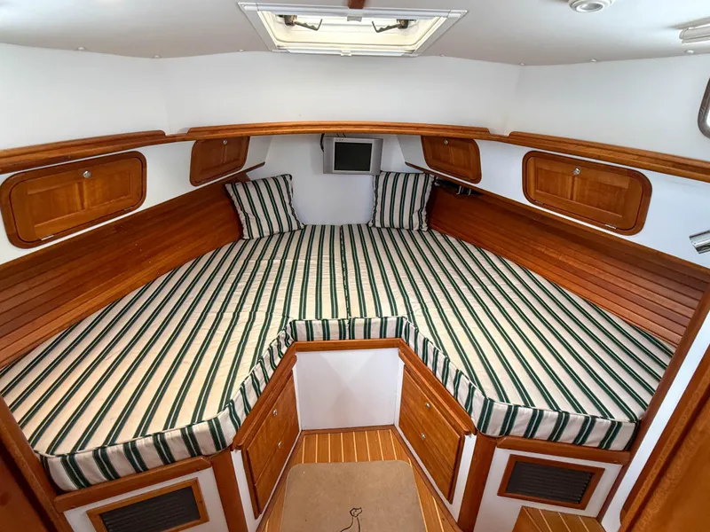 Slide: The Image of 2002 Legacy 34 Express cabin with striped bedding and wooden accents. - 32