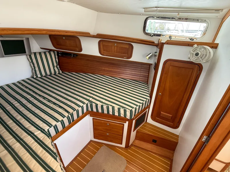 Slide: The Image of 2002 Legacy 34 Express cabin with striped bedding and wooden interior. - 33