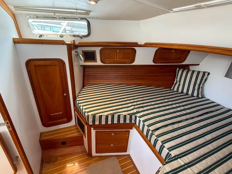 Slide: The Image of 2002 Legacy 34 Express cabin with striped bedding and wooden cabinetry. - 34