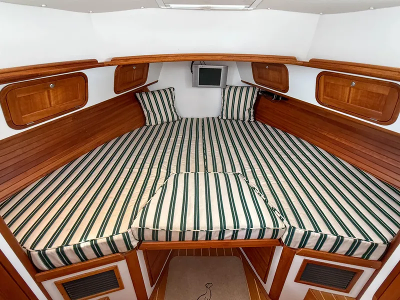 Slide: The Image of 2002 Legacy 34 Express cabin with striped bedding and wooden accents. - 35