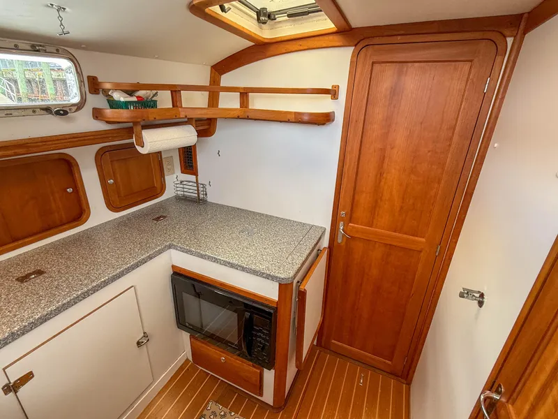 Slide: The Image of Legacy 34 Express 2002 boat interior with wooden cabinetry and compact kitchen area. - 38