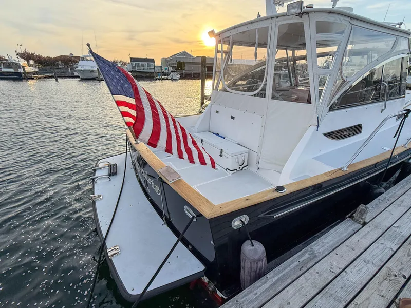 Slide: The Image of 2002 Legacy 34 Express boat docked at sunset with American flag. - 4