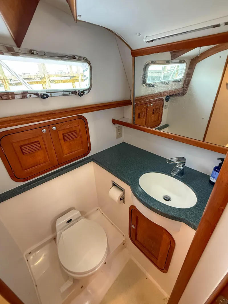 Slide: The Image of 2002 Legacy 34 Express yacht bathroom with sink, toilet, and wooden cabinetry. - 40