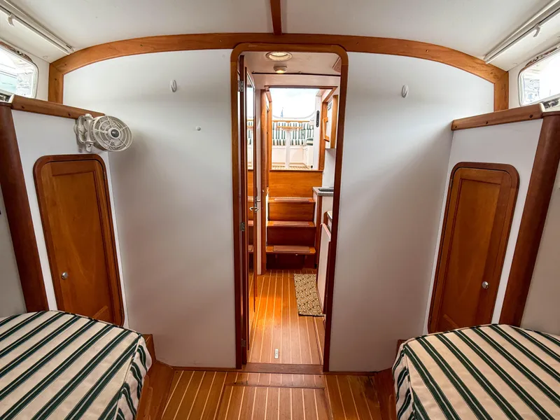 Slide: The Image of Interior of 2002 Legacy 34 Express boat with wood accents and striped bedding. - 42
