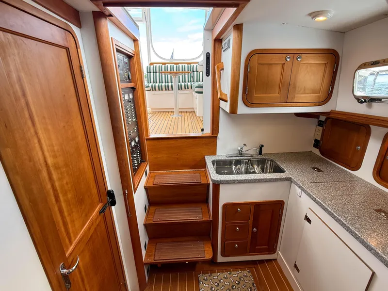 Slide: The Image of Interior of 2002 Legacy 34 Express boat with wooden cabinetry and compact kitchen area. - 43