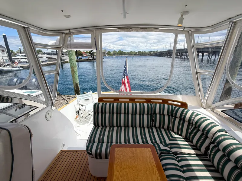 Slide: The Image of Interior view of 2002 Legacy 34 Express yacht with striped seating and waterfront backdrop. - 44